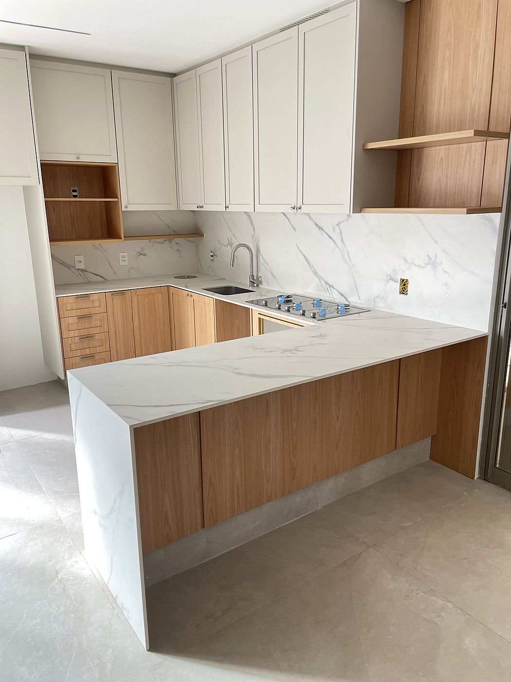 Cozinha em U com bancada marmorizada e frontão