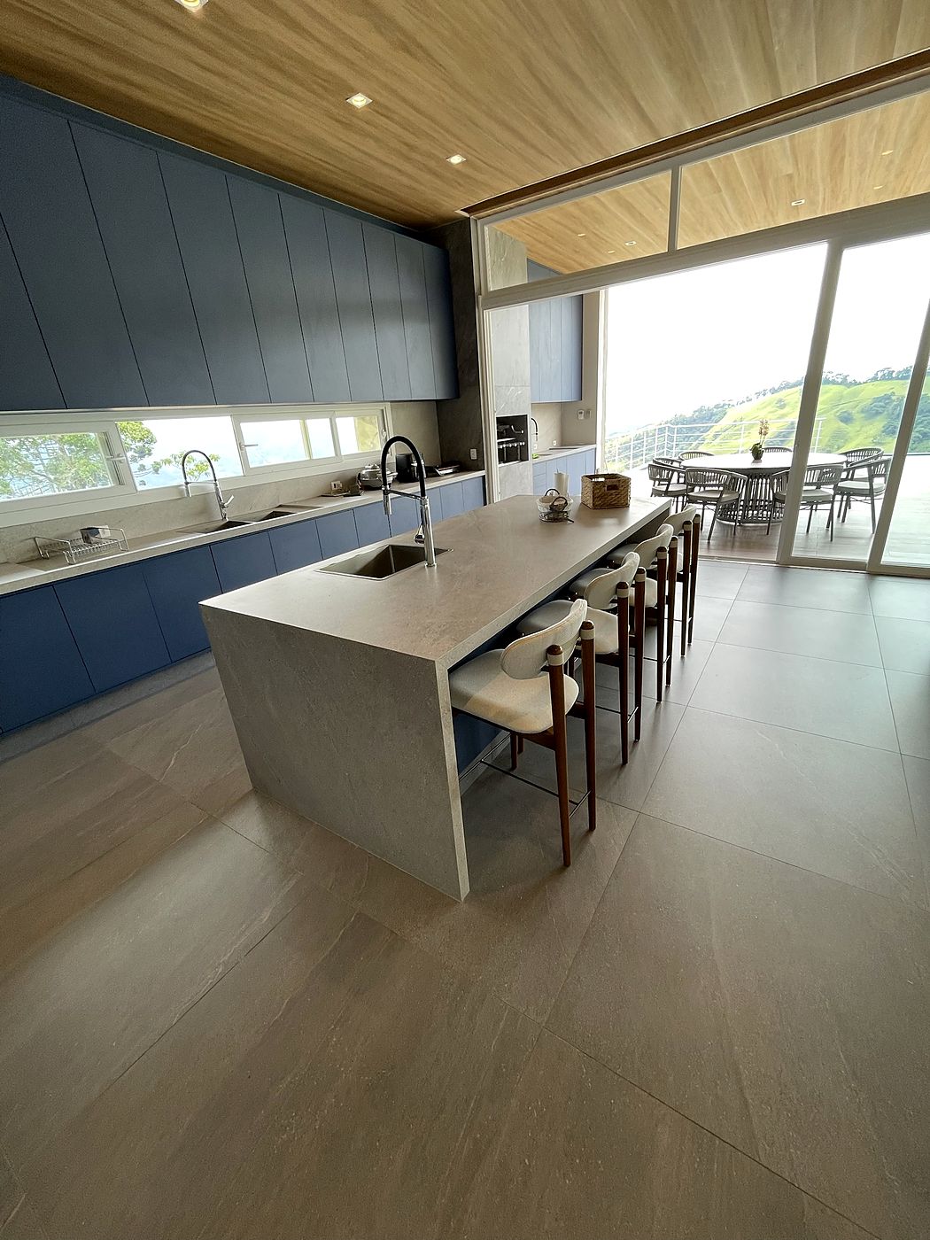 Ilha com cuba e laterais até o piso, em cozinha com vista para a serra